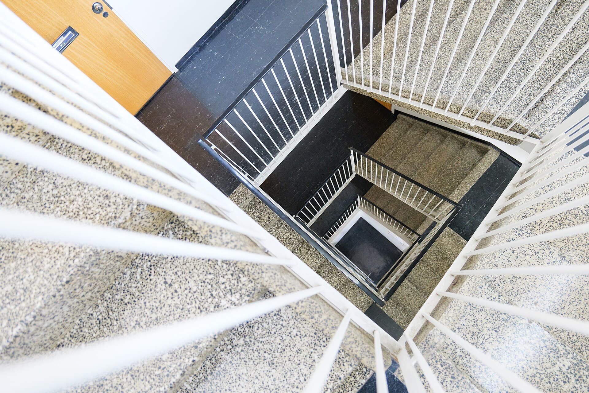 Kig ned gennem en lys trappeopgang med terrazzo-trin — ejendomsservice